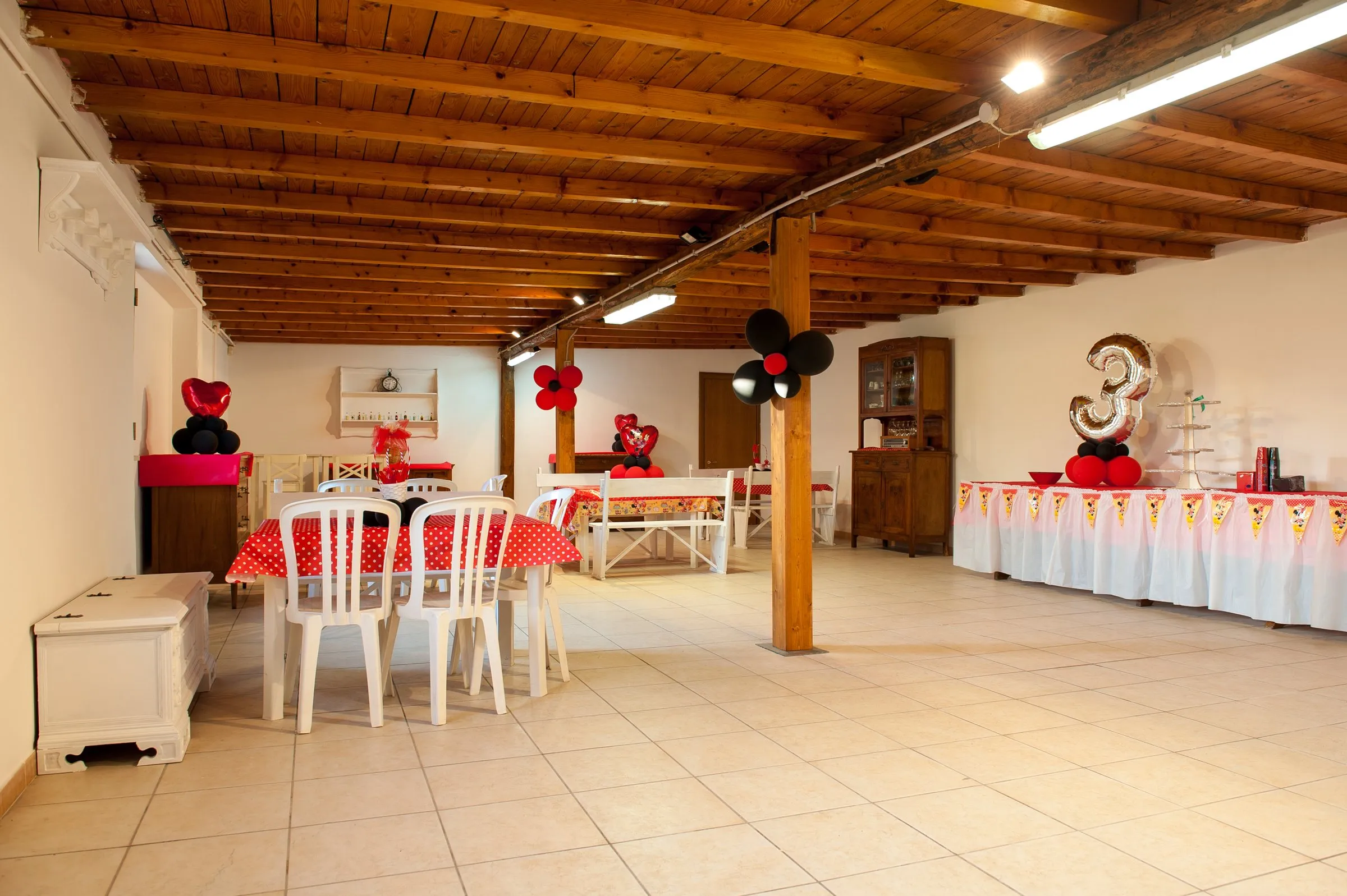 Sala allestita per una festa di compleanno a tema, con decorazioni a pois rosso e nero