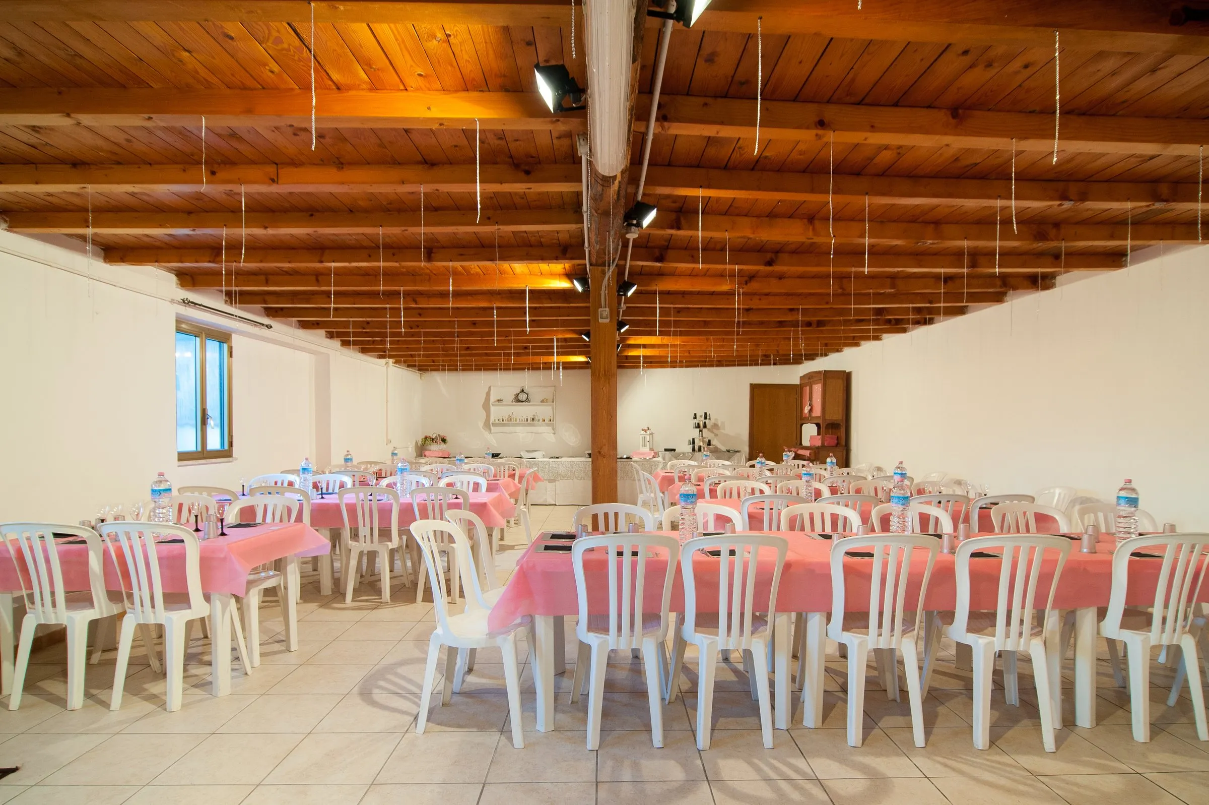 Vista d'insieme della sala allestita, con travi in legno a vista e tavoli pronti per gli ospiti