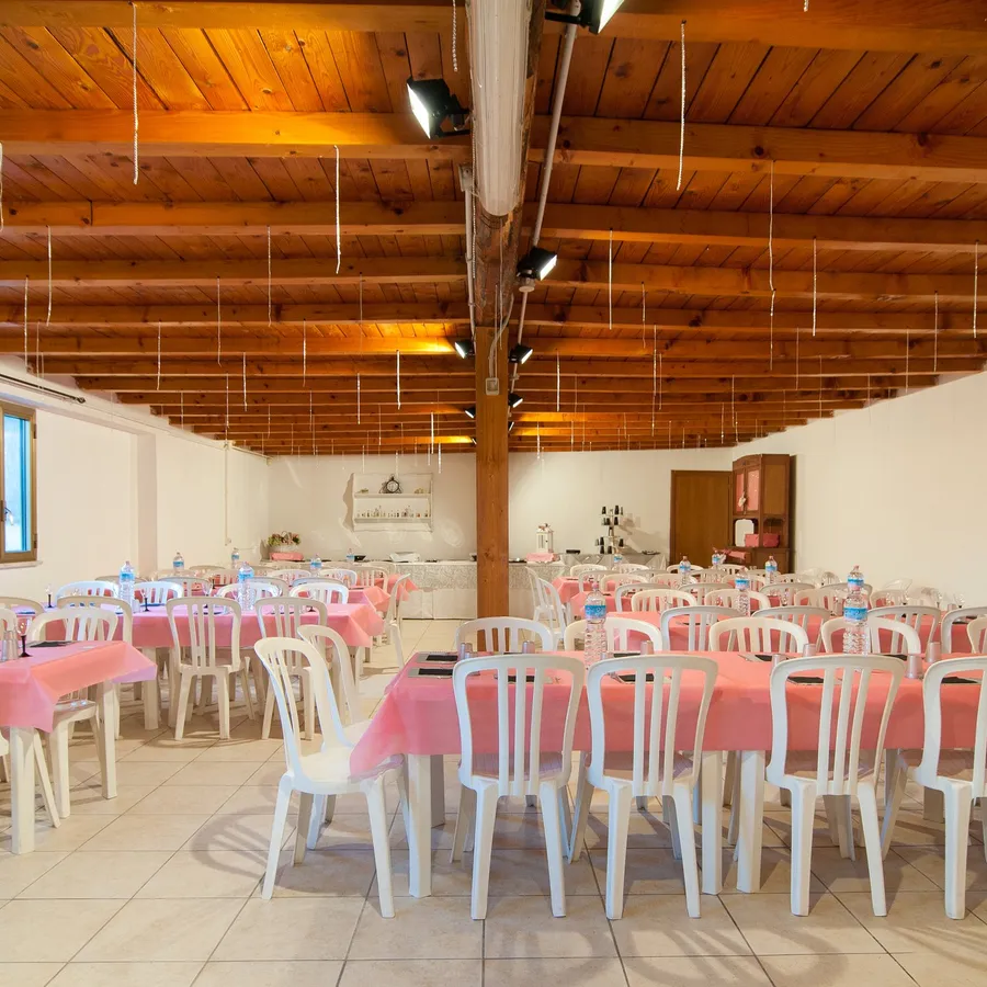 Vista d'insieme della sala allestita, con travi in legno a vista e tavoli pronti per gli ospiti